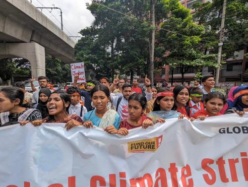  young people holding a banner during the Climate Strike in the streets of Dhaka
