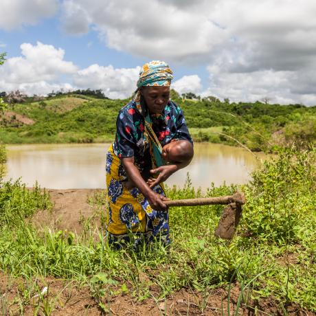 A woman farming with her baby in her arms