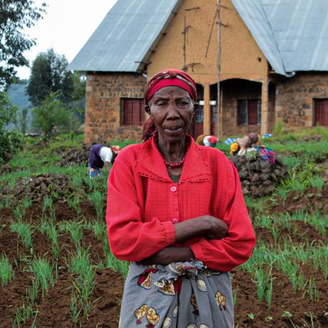 Asteria stands in front of her crops, Rwanda.