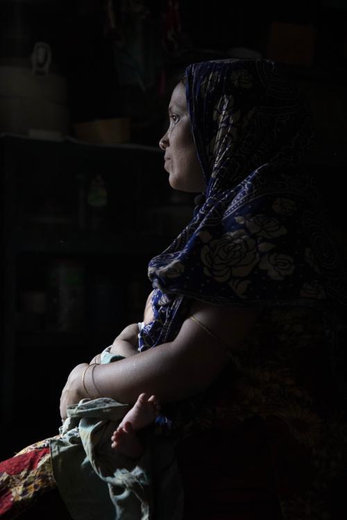 Shahanaz, holding 25-day-old baby Alifa, in their one-room home.