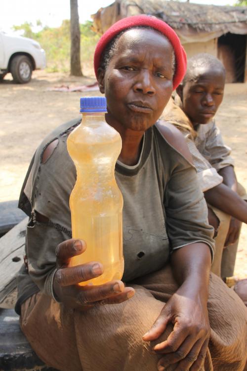 Esther Nalumgwe 64, a resident of Shimulala village, Chingola, showing water that she has drawn from the polluted rivers, which families in the area are forced to use.