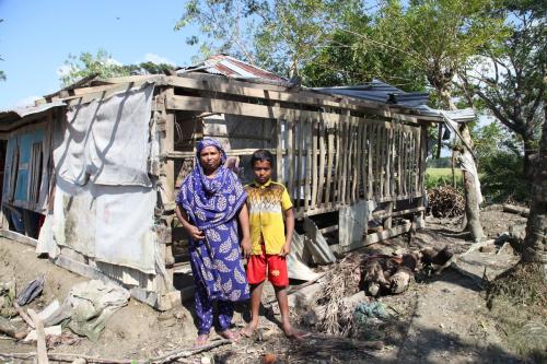 Jesmin and her son Rifat in front of their house that was damaged by Cyclone Bulbul