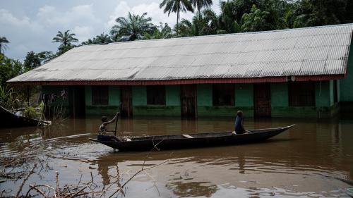 Children use a boat to navigate around their flooded community.