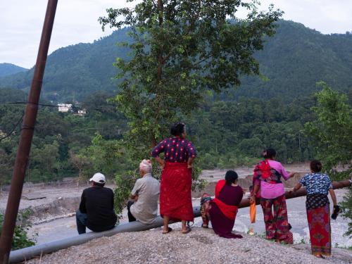 People gather beside the flood-hit Trishuli River in Trishuli Bazar, Nuwakot. 