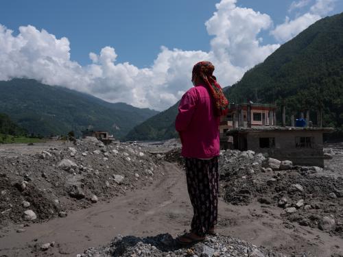 Durga looks over what remains of her farmland in Tupche, Nuwakot, Nepal. Her home was destroyed and livestock lost in the floods, forcing her family to shelter with a neighbour.
