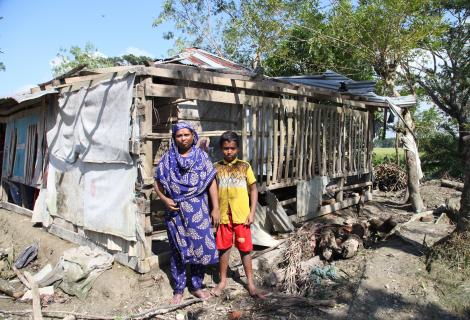 A mother and child stand outside their ruined home in Bangladesh