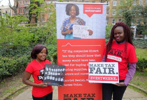 Two women holding posters calling for fair taxation