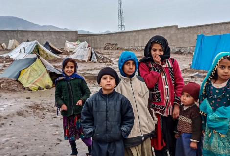 Children stand in front of tents in a camp for internally displaced people in Afghanistan