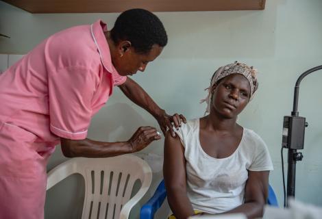 A nurse in Uganda is giving a woman an injection 