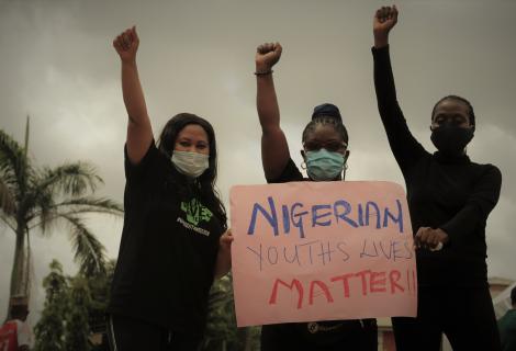Young women protest against police violence in Nigeria holding a pink sign that says 'Nigerian lives matter'