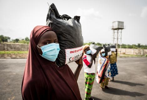 Women from Tungan Nasara community carry their relief packages as they prepare to return to their home