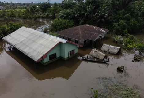 Children use a boat to navigate around their flooded community.