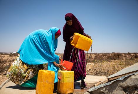 Two women pour water into containers, Somaliland