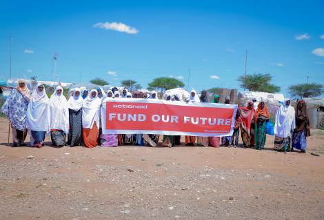 Women hold a banner saying fund our future. 