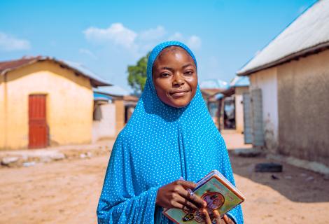 Fauziya, a student from Nigeria, standing in front of her home 