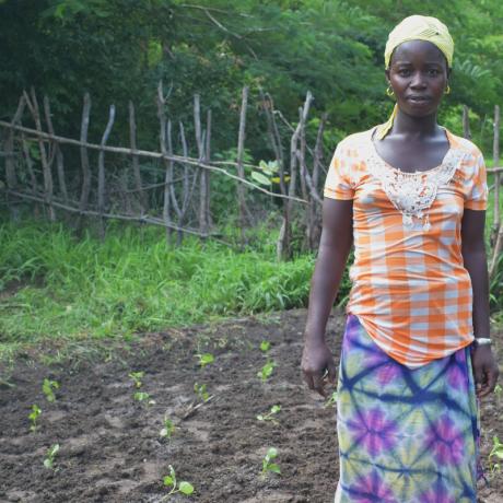 Fatou Keita, 32, is a farmer and manages her household in Bakho, Senegal. She stands in smallholding, surrounded by green shoots