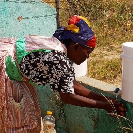 A woman in rural Zimbabwe washes her hands from a plastic container 