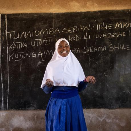 Photo of a female school student in front of a chalk board