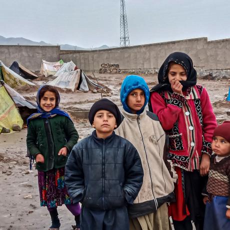 Children stand in front of tents in a camp for internally displaced people in Afghanistan