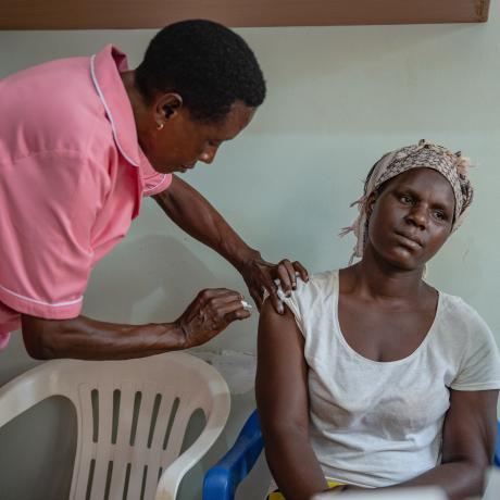 A nurse in Uganda is giving a woman an injection 