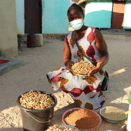 Mavis, a young smallholder farmer from Zimbabwe sits surrounded by her produce 