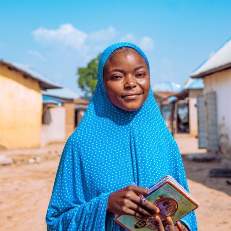 Fauziya, a student from Nigeria, standing in front of her home