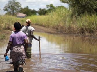 Women walking along a flooded path in Buzi, Mozambique