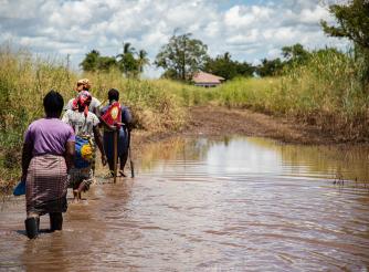women wade through flood water in mozambique 