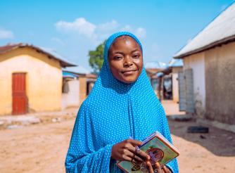 Fauziya, a student from Nigeria, standing in front of her home 