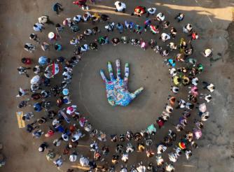 Photo is an aerial view of an embroidered hand surrounded by a crowd of young activists