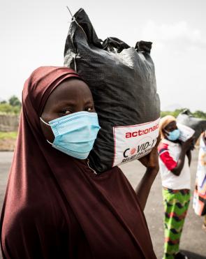 Women from Tungan Nasara community carry their relief packages as they prepare to return to their home