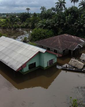Children use a boat to navigate around their flooded community.