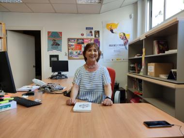 Image of Juana Bengoa, smiling at the camera in her office
